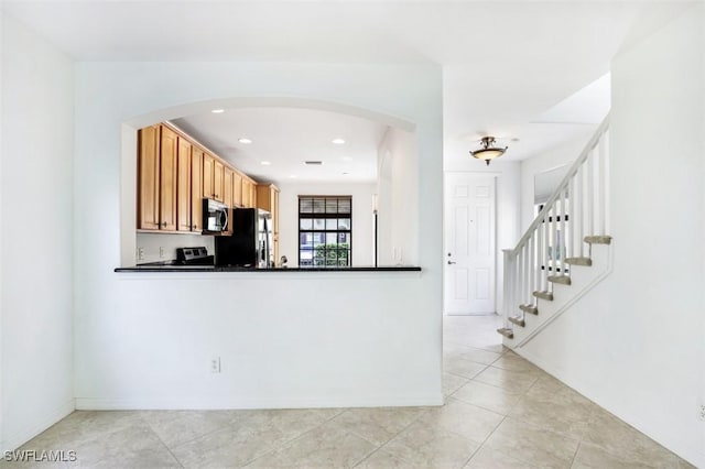 kitchen with black refrigerator, stove, and light tile patterned floors