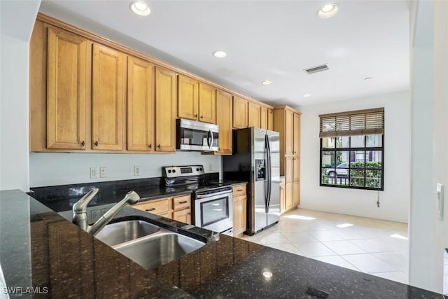 kitchen featuring light tile patterned floors, stainless steel appliances, dark stone countertops, and sink