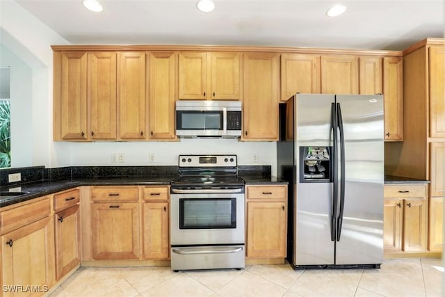 kitchen with dark stone countertops, light tile patterned floors, sink, and appliances with stainless steel finishes