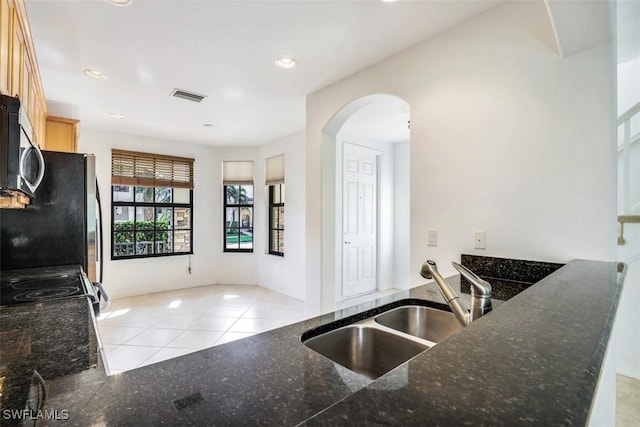 kitchen with sink, light tile patterned floors, light brown cabinetry, fridge, and kitchen peninsula