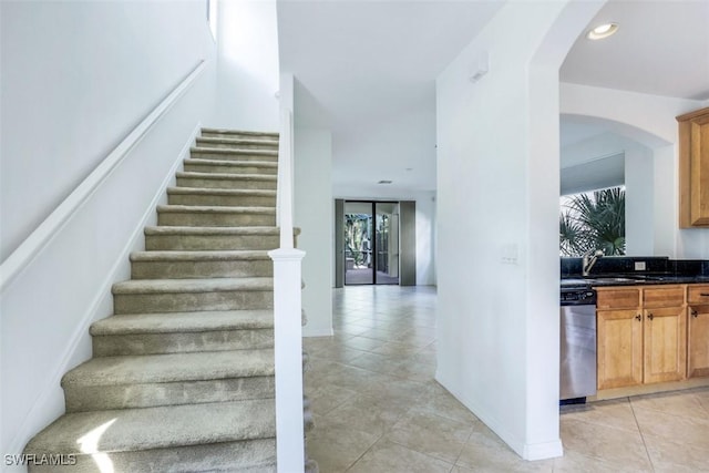 stairs with tile patterned flooring, a wall of windows, and sink