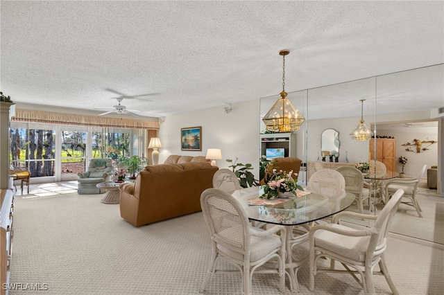 dining space featuring ceiling fan with notable chandelier, light colored carpet, and a textured ceiling