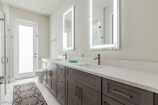 full bathroom featuring toilet, double vanity, visible vents, and a sink