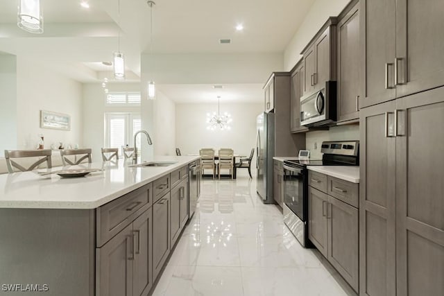 kitchen featuring appliances with stainless steel finishes, a large island with sink, a sink, and hanging light fixtures