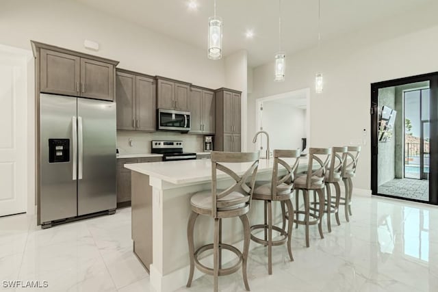 kitchen featuring marble finish floor, decorative light fixtures, stainless steel appliances, light countertops, and decorative backsplash