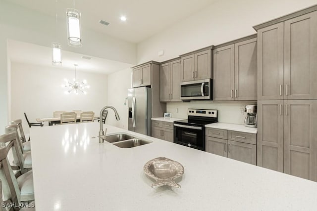 kitchen featuring light countertops, stainless steel appliances, a sink, and decorative light fixtures