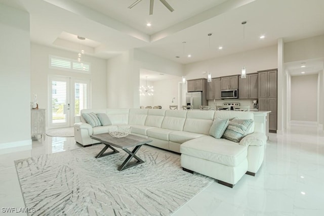 living area featuring recessed lighting, a towering ceiling, baseboards, marble finish floor, and a tray ceiling