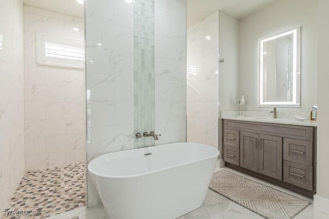 bathroom featuring marble finish floor, walk in shower, a freestanding tub, and vanity