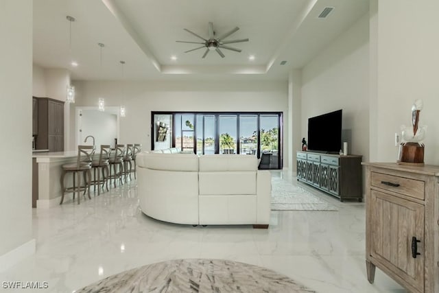 living area with marble finish floor, recessed lighting, a raised ceiling, visible vents, and ceiling fan