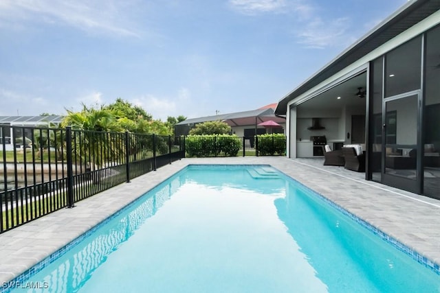 view of swimming pool featuring a grill, fence, an outdoor kitchen, and a fenced in pool