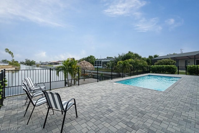 view of swimming pool with a patio area, a water view, fence, and a fenced in pool