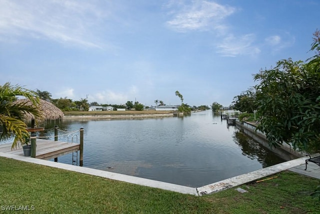 view of dock with a lawn and a water view