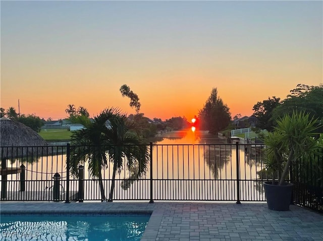 gate at dusk with a fenced in pool and a water view