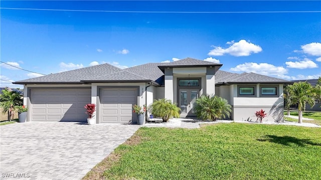 prairie-style house with a garage, a front lawn, decorative driveway, and stucco siding