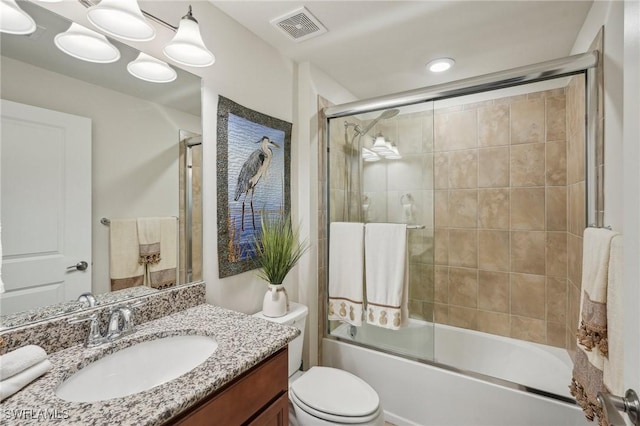 full bathroom featuring bath / shower combo with glass door, vanity, and toilet