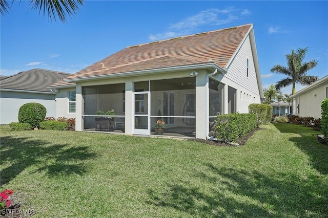 rear view of house featuring a sunroom and a lawn