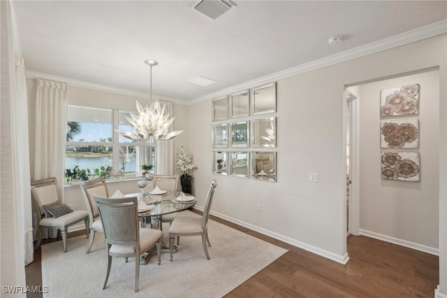 dining room with hardwood / wood-style flooring, ornamental molding, a water view, and a chandelier