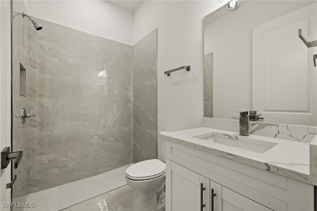 bathroom featuring vanity, tiled shower, and toilet