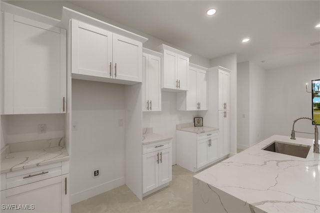 kitchen featuring sink, white cabinetry, and light stone counters