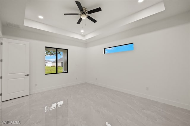 spare room with ceiling fan and a tray ceiling