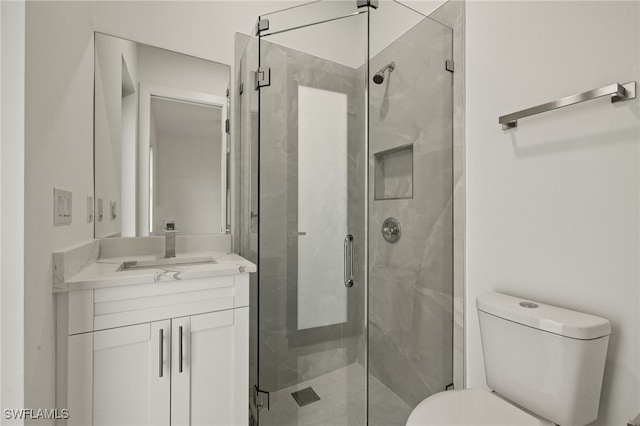 bathroom with toilet, a shower with door, and vanity