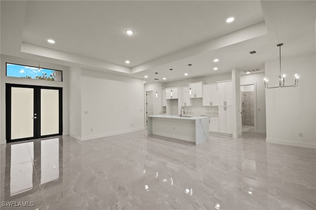 unfurnished living room with sink, an inviting chandelier, and a tray ceiling