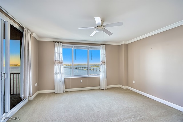 carpeted empty room featuring ceiling fan, a water view, and ornamental molding