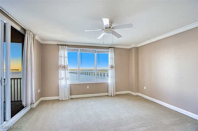 carpeted spare room with crown molding, a ceiling fan, and baseboards