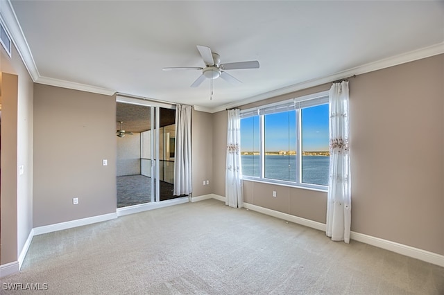 empty room featuring light carpet, a water view, ceiling fan, and ornamental molding