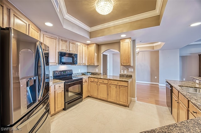 kitchen with a raised ceiling, a chandelier, black appliances, and ornamental molding