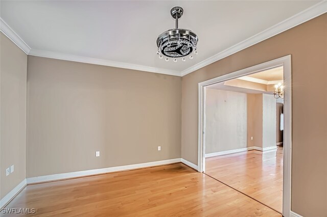 unfurnished room featuring crown molding, baseboards, a notable chandelier, and light wood-style floors