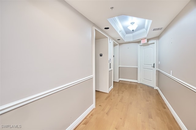 hall with light wood-type flooring and a tray ceiling