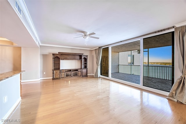 unfurnished living room with a ceiling fan, visible vents, wood finished floors, baseboards, and ornamental molding