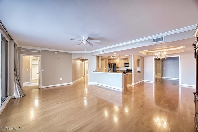 unfurnished living room with a raised ceiling, light wood-type flooring, ceiling fan with notable chandelier, and ornamental molding