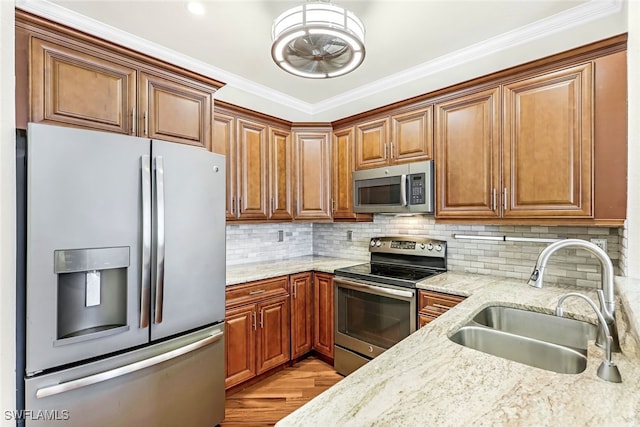 kitchen with appliances with stainless steel finishes, backsplash, light stone counters, and sink