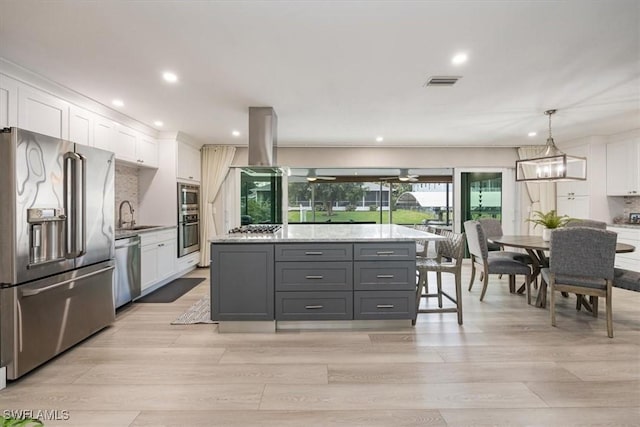 kitchen with appliances with stainless steel finishes, a kitchen island, decorative light fixtures, white cabinetry, and decorative backsplash