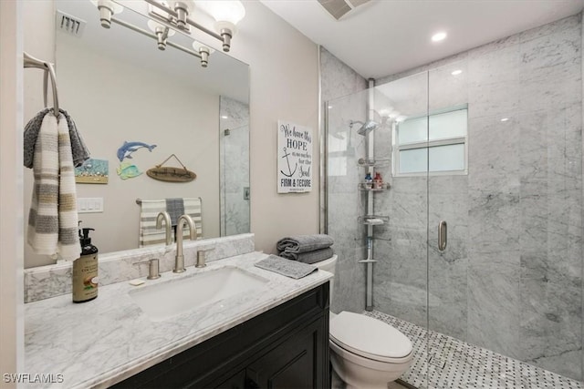 bathroom featuring a shower with shower door, toilet, and vanity