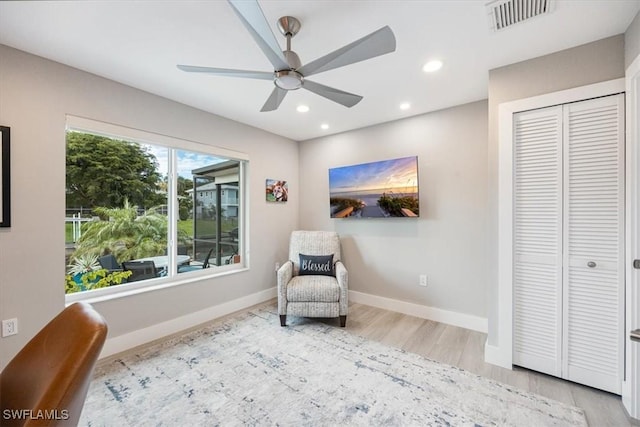 living area featuring light hardwood / wood-style floors and ceiling fan