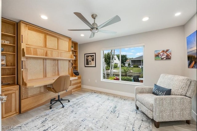 office featuring built in desk, light wood-type flooring, and ceiling fan