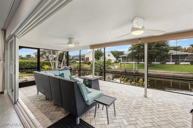 sunroom / solarium featuring a water view, a healthy amount of sunlight, and ceiling fan