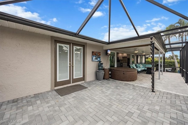 view of patio with a hot tub, french doors, outdoor lounge area, ceiling fan, and a lanai