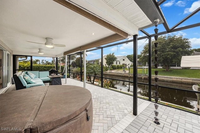 sunroom featuring ceiling fan and a water view