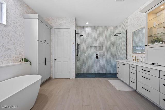 bathroom featuring hardwood / wood-style flooring, vanity, and plus walk in shower