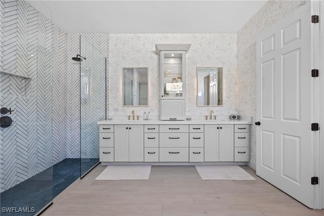 bathroom with a tile shower and vanity