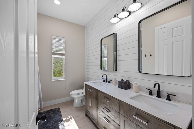 bathroom with vanity, toilet, and wooden walls