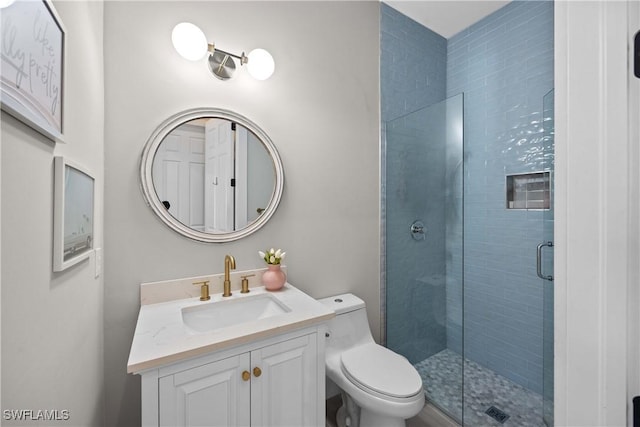 bathroom featuring vanity, toilet, and a shower with door