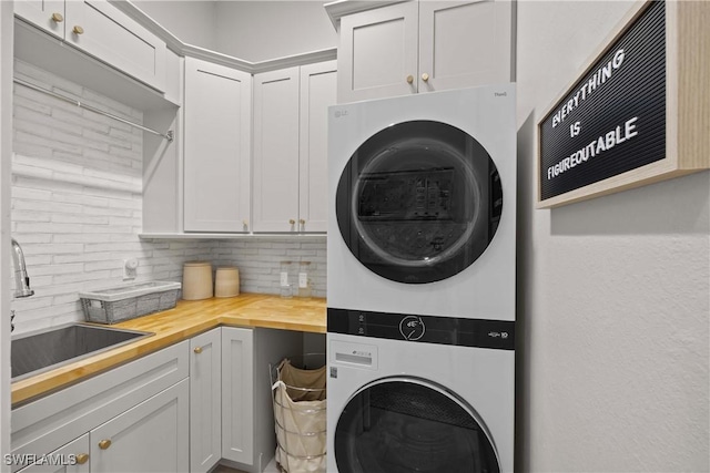 laundry area with sink, cabinets, and stacked washer / drying machine