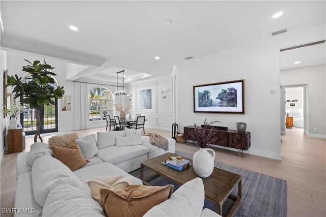 living room with ornamental molding, light hardwood / wood-style floors, and a notable chandelier