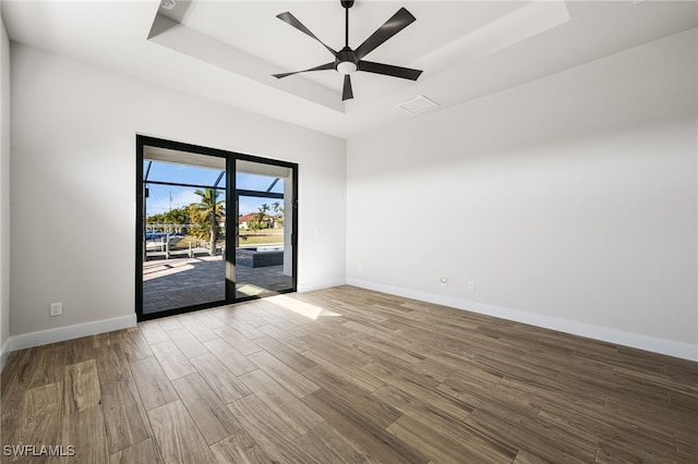 spare room featuring ceiling fan, wood-type flooring, and a tray ceiling