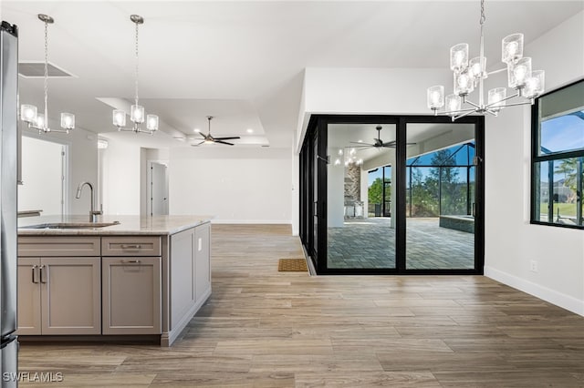 kitchen with light stone countertops, sink, pendant lighting, and gray cabinets